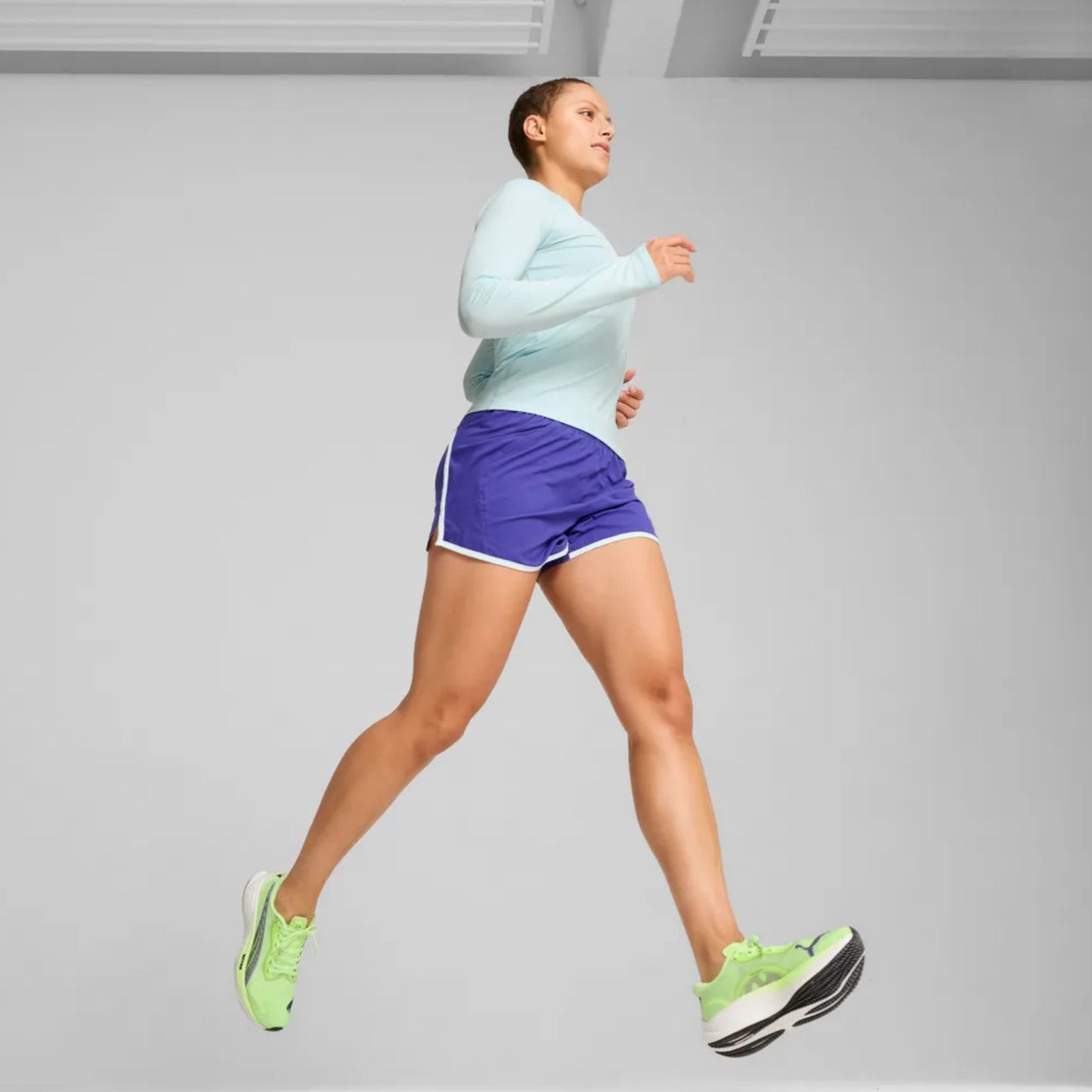 Person running with green Pon a plain backgroundma running shoes
