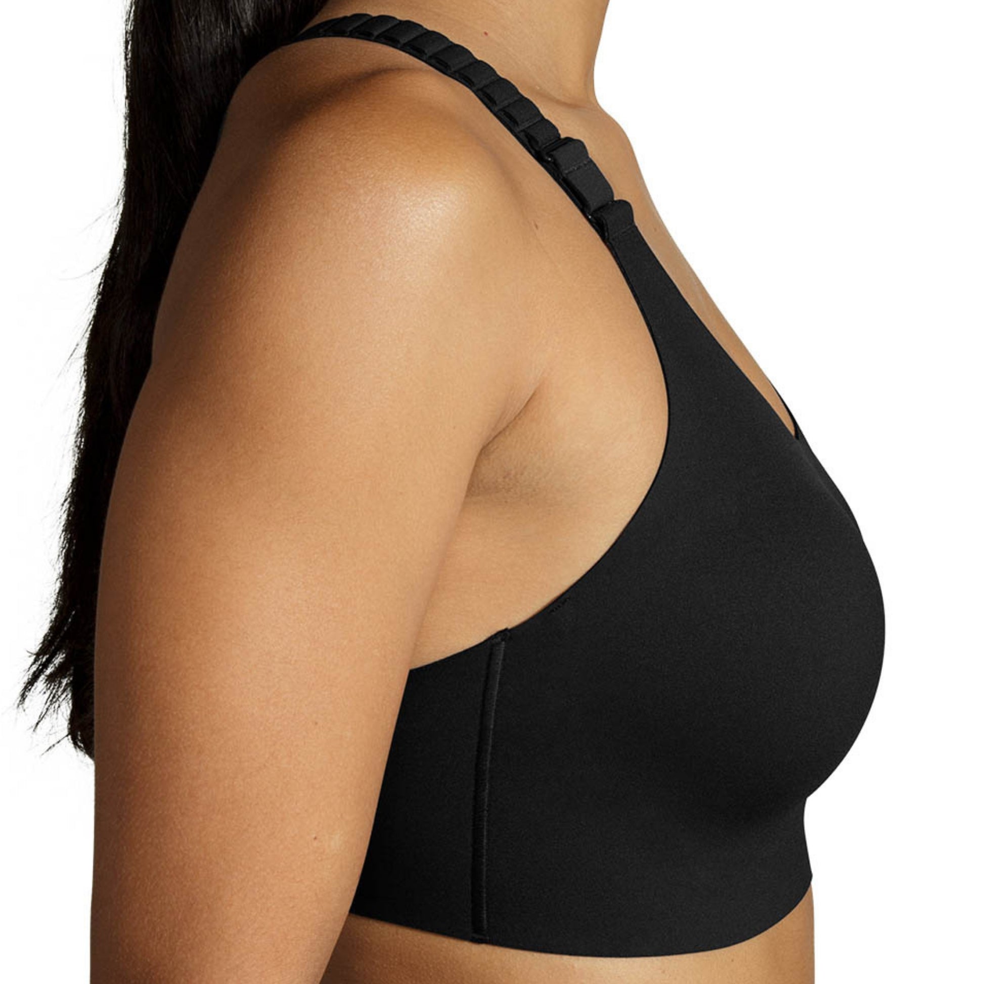 Close-up side view of a woman wearing a black sports bra with a braided shoulder strap against a plain white background.