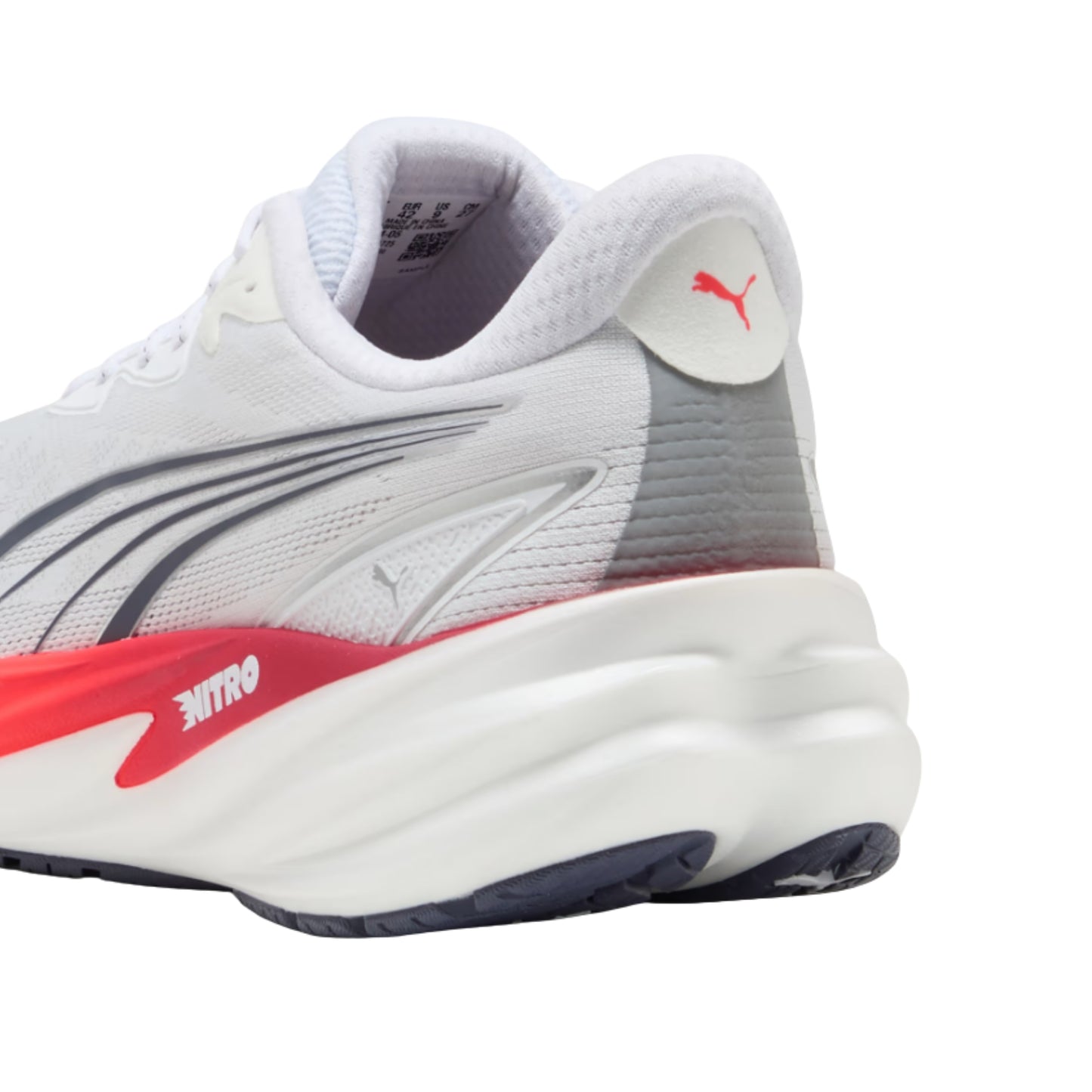 A close-up side view of a Puma running shoe in white, gray, and red, showing the side stripe, heel logo, and midsole details against a white background.