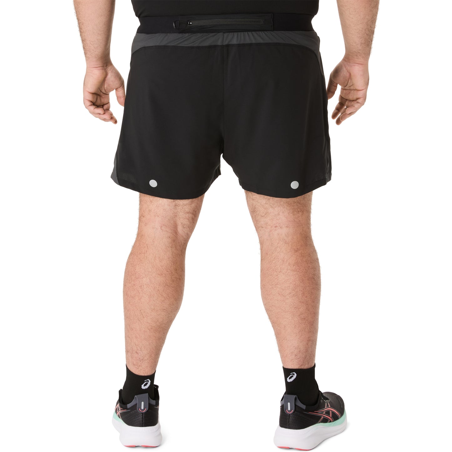 Person wearing black Asics running shorts on a white background