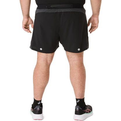 Person wearing black Asics running shorts on a white background