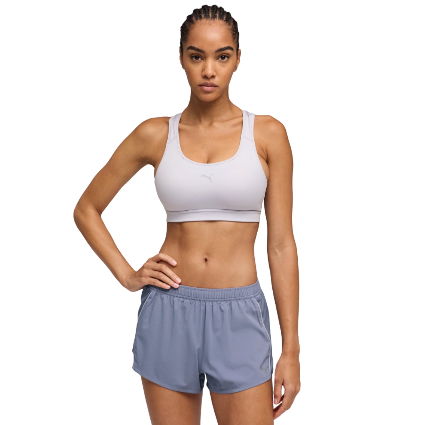 Woman wearing a white Puma sports bra and gray shorts on a white background