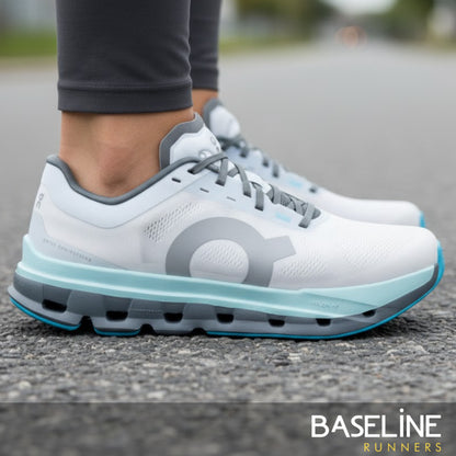 White and gray running shoes with a visible brand logo on a road background