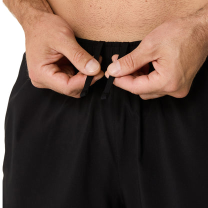 Person adjusting a black drawstring waistband on running shorts against a white background