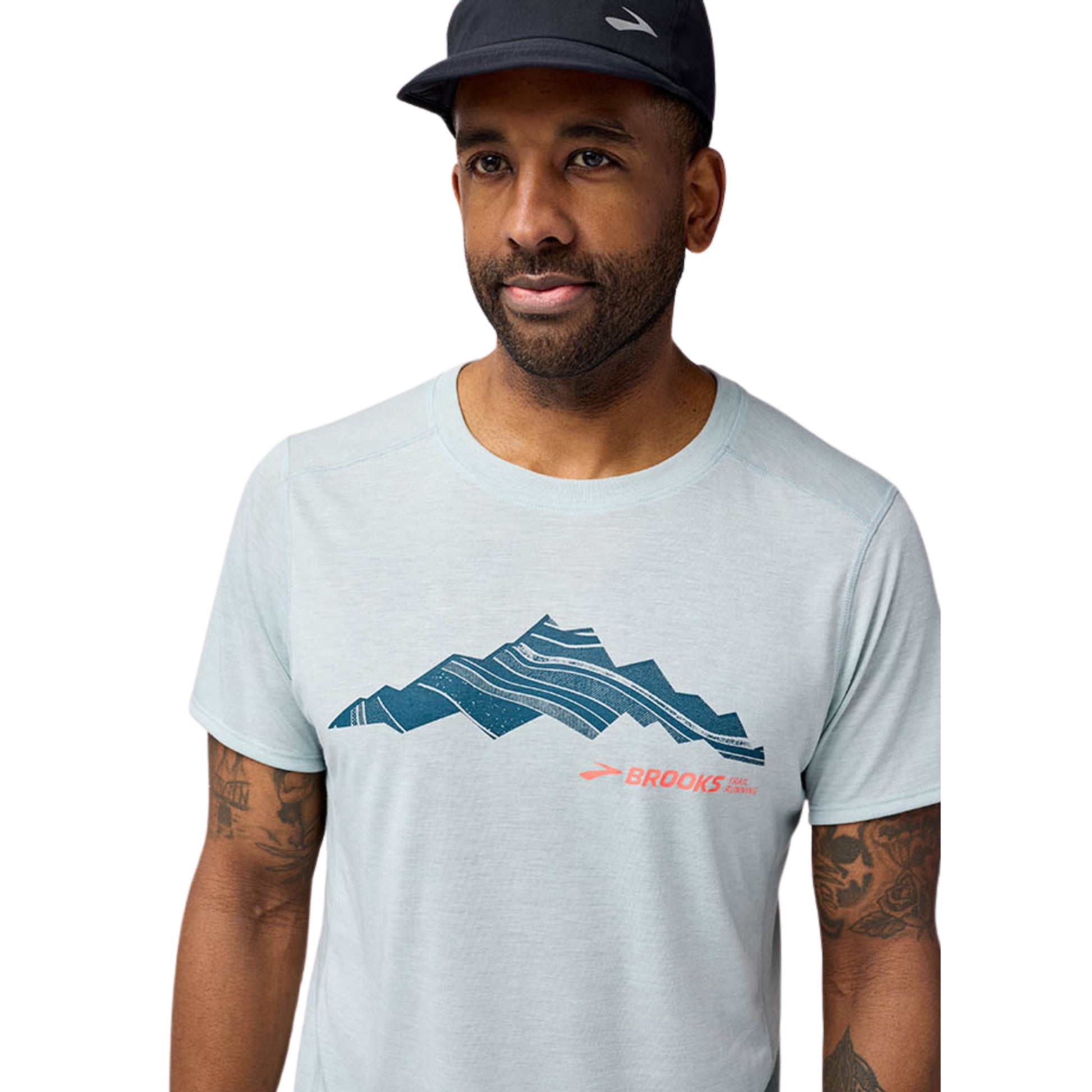 Man wearing a light gray t-shirt with a mountain graphic and Brooks logo on a white background