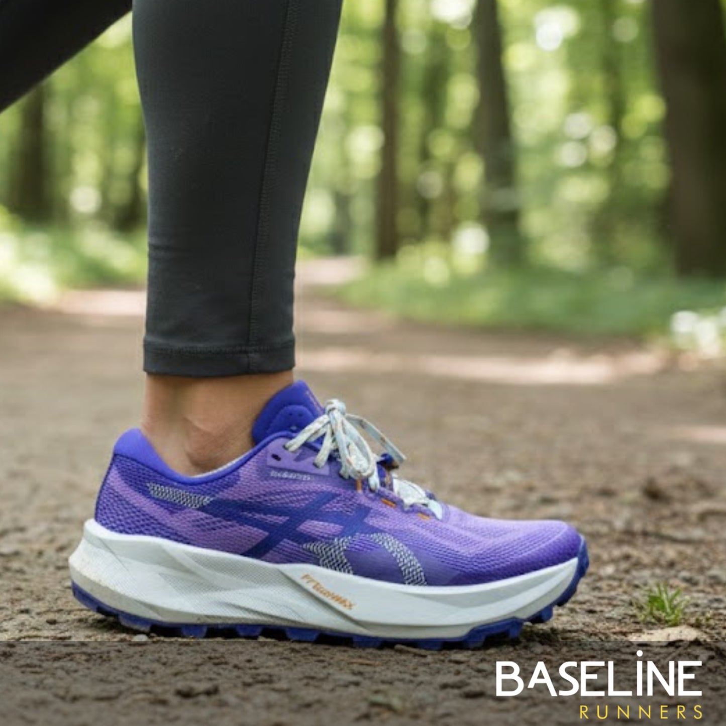 Purple Asics running shoe on a person's foot with a blurred forest background