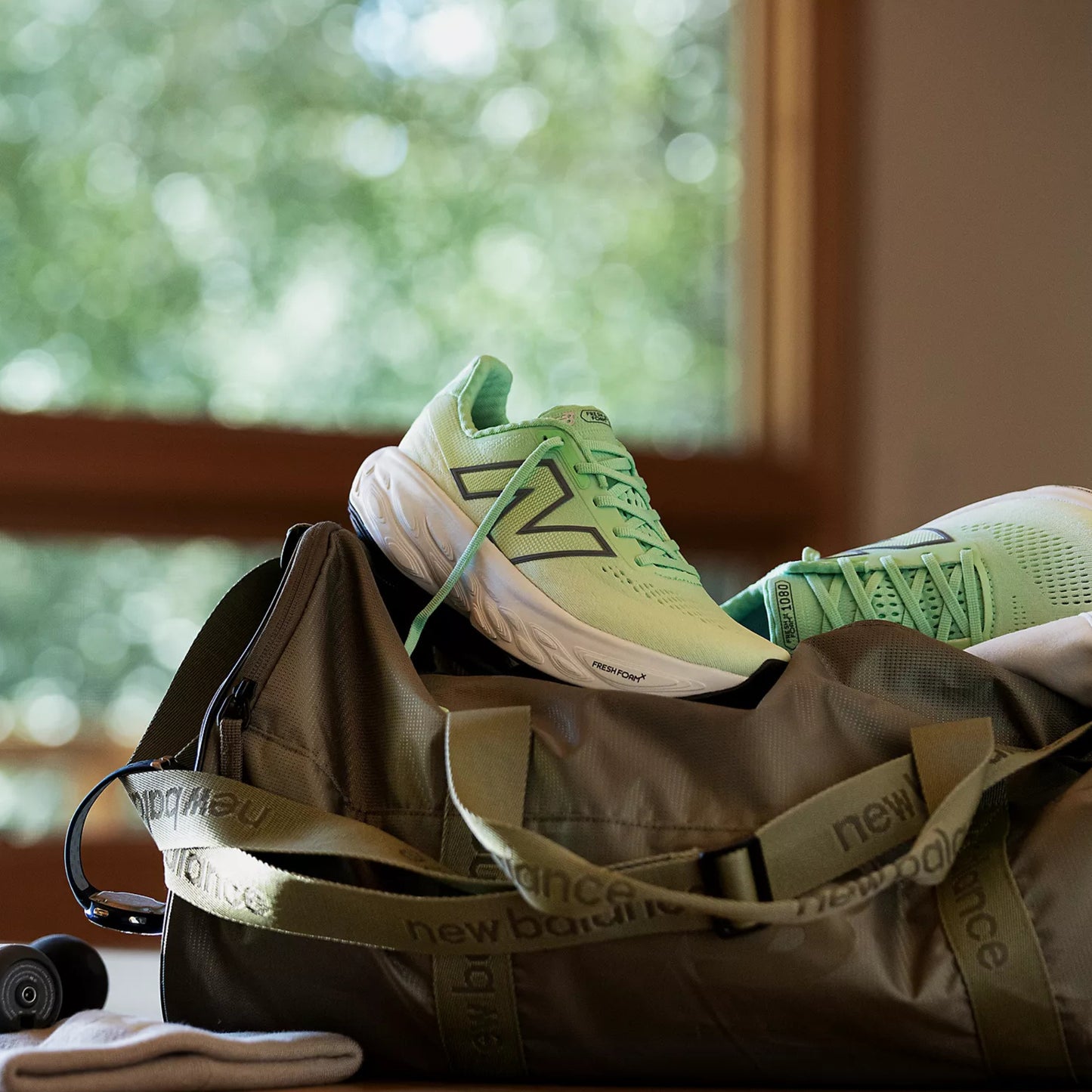 Green sneakers on a brown duffel bag with a blurred green outdoor background