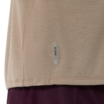 Close-up of a beige athletic top with a small vertical reflective strip reading ACTIBREEZE, shown against a white background with a dark purple garment partially visible below.